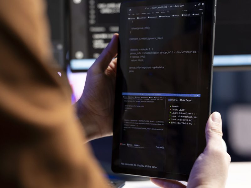 Teleworking programmer designing and developing software applications using tablet. IT administrator implementing and maintaining company systems using portable device, close up